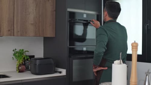 Male Chef Opening and Closing Oven in Modern Kitchen