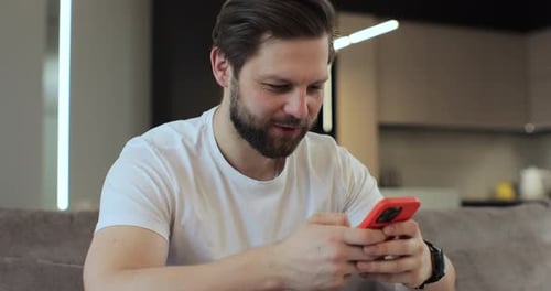 Man Relaxing with Mobile Phone in Cozy Living Room Close Up Portrait Browsing the Internet and