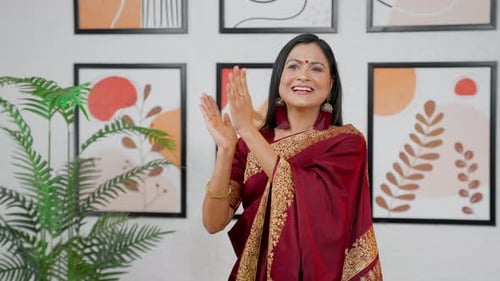 Smiling Woman Clapping Indoors in Maroon Sari