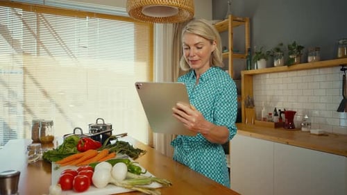 Woman Uses Tablet to Prepare Food in Kitchen