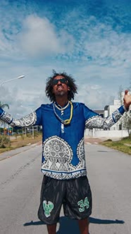 Homem africano em roupas autênticas fica com as mãos estendidas na rua e no fundo urbano