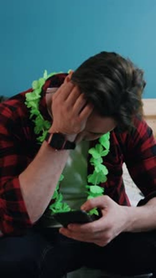 Casual Reflection A Man Wearing Colorful Hawaiian Leis While Engaged with His Smartphone