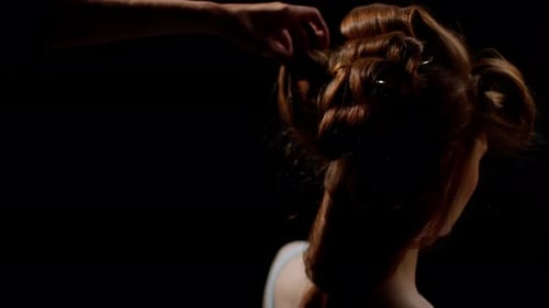 Hairdresser Styling a Young Woman's Reddishbrown Hair in an Intricate Braid with a Closeup of the