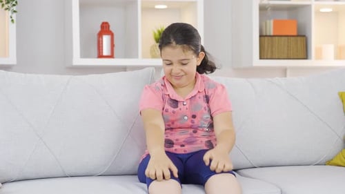 Child Itching Uncomfortably on Couch Indoors