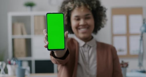 African American Businesswoman Showing Smartphone with Chroma Key Green Screen Smiling in Office