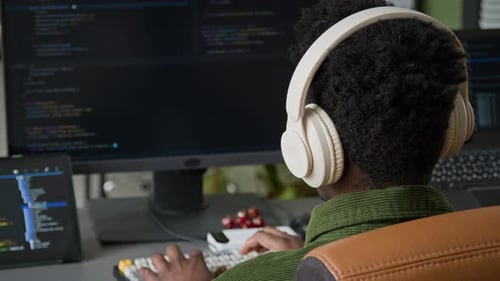 Desarrollador Hombre Negro Con Auriculares Escribiendo Código Mientras Diseña una Aplicación Móvil