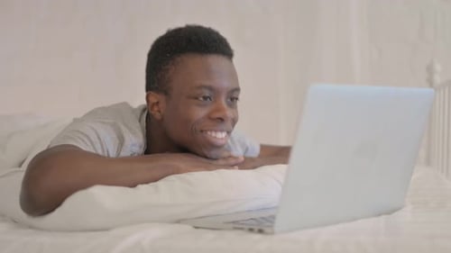 Smiling Man Video Calls From Bed On Laptop