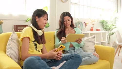 Two Young Women Chatting with Technology on Couch