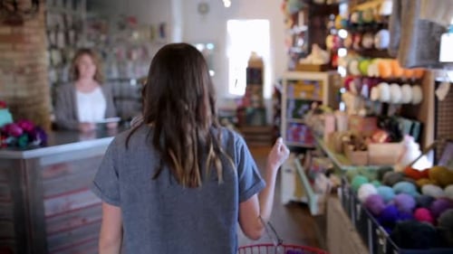 Woman approaches cash register to pay for colorful yarn at a local store