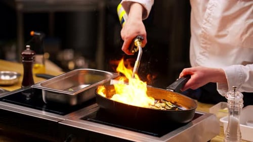 Close Up Chef Frying Different Vegetables on a Hot Frying Pan with Torch on the Stove
