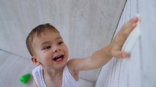 Adorable Child Reaches for Wall in Bright Room