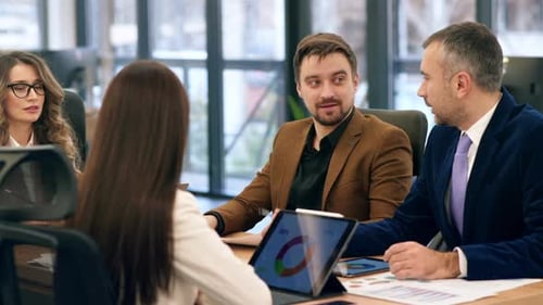 Business meeting in an office, workers discussing business affairs. Gadgets and papers with charts o