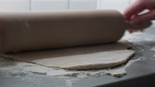 Hands Rolling Dough with Rolling Pin in Kitchen