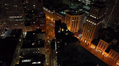 Survolez la ville nocturne, inclinez vers le bas les voitures qui traversent une intersection routière, des rues illuminées et