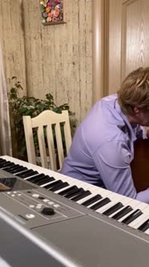Man Teaches Child How to Play Guitar at Home