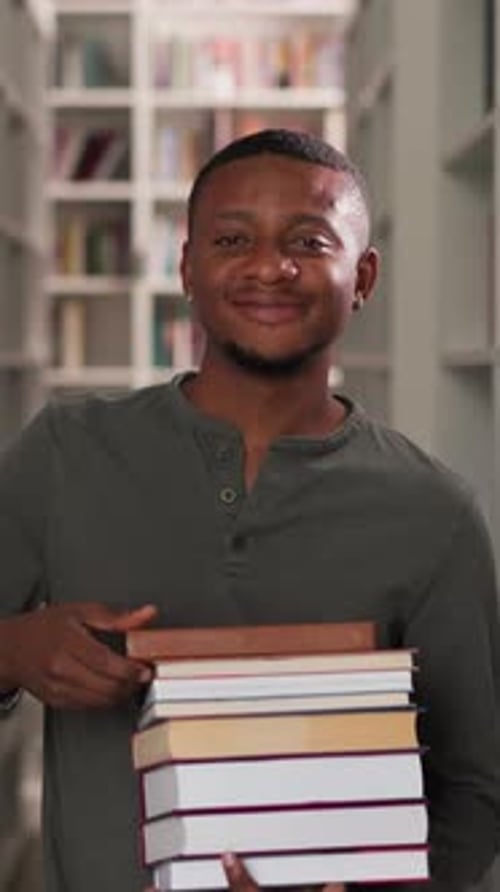 Happy Man Holds Book Stack in Public Library