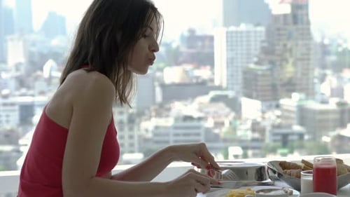 Woman enjoying breakfast with city view