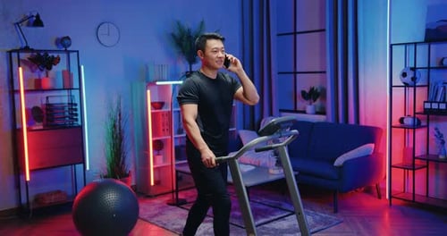 Man Talking on Phone Walking on Treadmill at Home