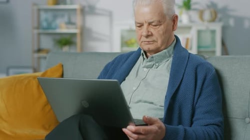 Senior man using laptop on sofa at home