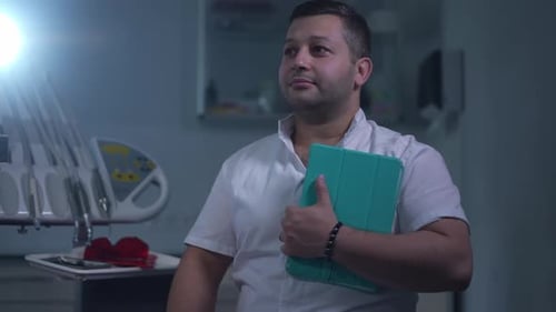 Foto mediana de un médico de Oriente Medio confiado con una tableta digital mirando hacia otro lado y girando hacia