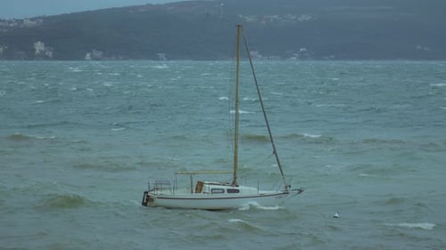 Sailboat struggles against waves in during a storm