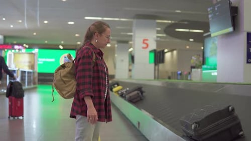 Female tourist with backpack is waiting her luggage in airport