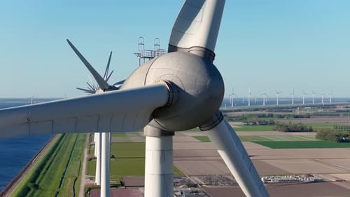 Aerial view of wind turbines on green fields near sea coast and dam.