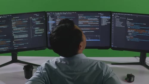 Asian Man Developer Having Backache While Write Code With Multiple Computer Screens In Green Screen