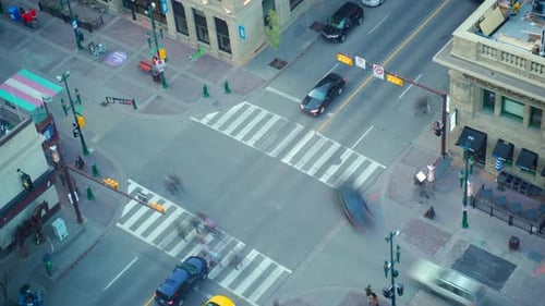 Time lapse of downtown street where people are crossing the street on crosswalks.