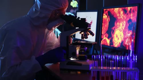 A man in biological defense works in a viral laboratory. He looks at the samples under an microscope