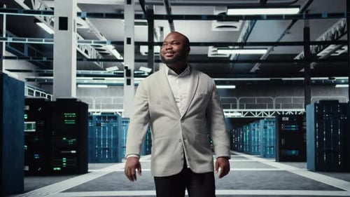 Smiling Engineer Walking in Data Center Checking Hardware for System Stability