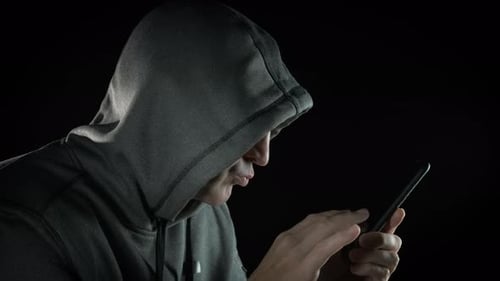 Hooded Person Using Mobile Phone in Dark