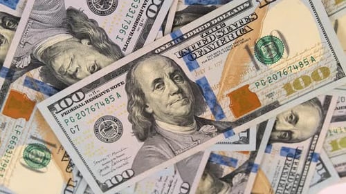 Many hundreds of American dollars on table slowly spinning close-up, view from above.