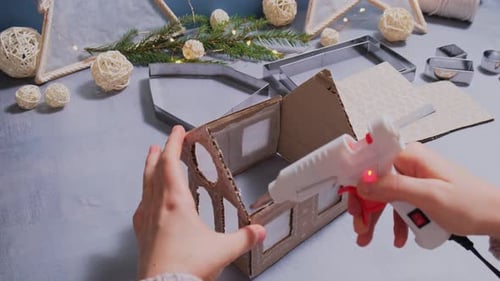 Hands Crafting Holiday Cardboard House Decoration