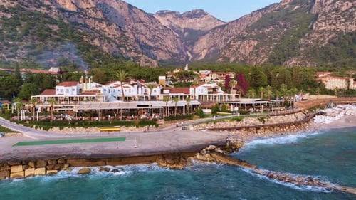 Gentle Waves Wash Against the Rocky Shore of a Picturesque Coastal Resort Town Nestled Amidst Lush