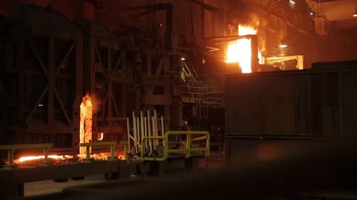 Molten metal pouring in a dimly lit steel mill, highlighting intense industrial processes