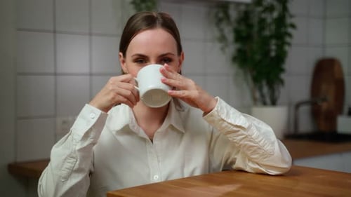 Woman Enjoying Warm Drink in Cozy Kitchen Setting