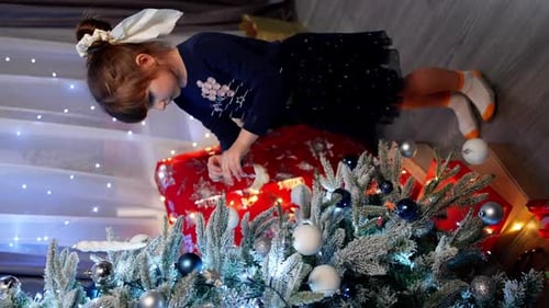 Girl Decorates Christmas Tree with Festive Ornaments