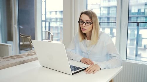 junge freiberufliche Geschäftsfrau, die online per Konferenz oder Videoanruf per Laptop-Webcam zu Hause arbeitet