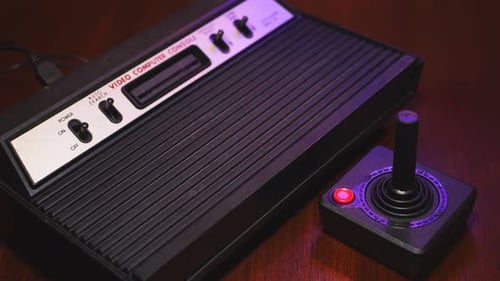 Close-Up Of Vintage TV Video Game Console Computer With Joystick On Wooden Table.