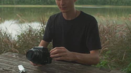 Young Adult Assembling Camera Outdoors by Lake