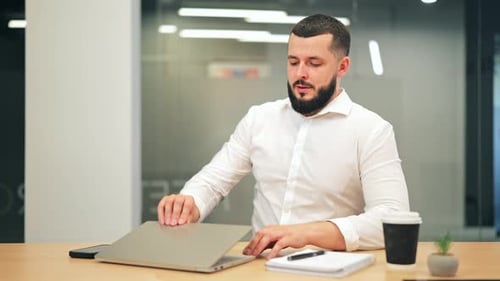 Satisfied Professional Man Closes Laptop in Modern Office