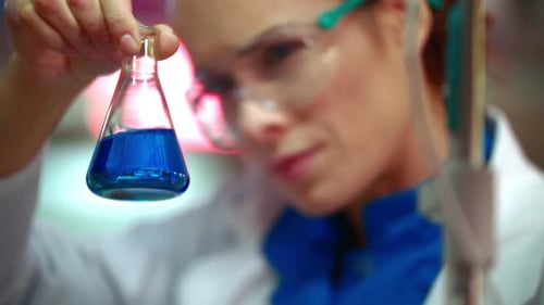 Woman Scientist Holding Beaker with Blue Liquid