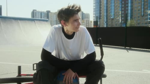 Young BMX Rider Sitting on Bike at Skate Park and Posing on Camera