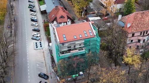 Building renovation underway on a multistory structure in a tree-lined neighborhood aerial view