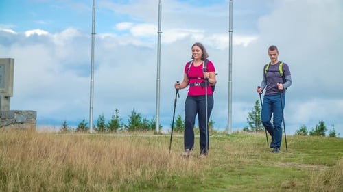 Young hiker couple enjoying trekking through the bushy plains on a cloudy day. Slow motion, Front vi