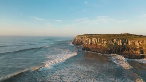 Drone aerial view of tropical beach rocky cliffs on atlantic ocean at sunrise