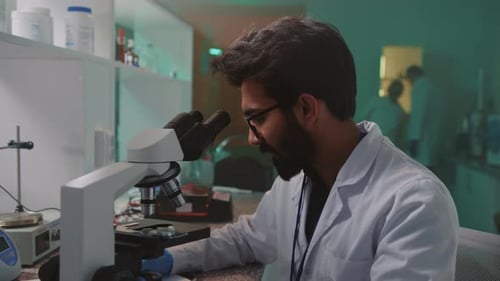 Focused Researcher Using Microscope in Bright Laboratory