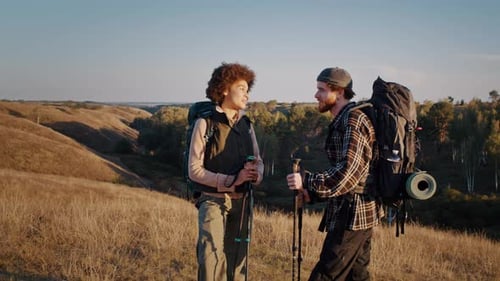 Romantic Mixed Race Couple with Nordic Walking Sticks on Hill