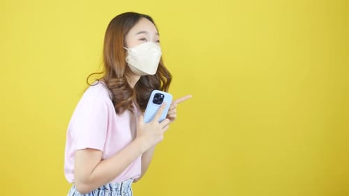 Nahaufnahme einer Video Frau mit Gesichtsmaske, Smartphone in der Hand und Schilder zeigt, die für Produ werben